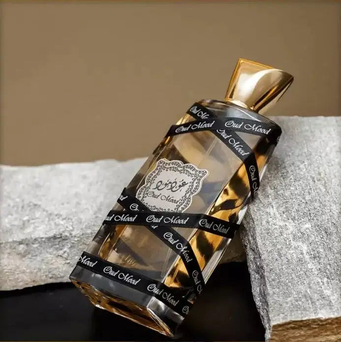 Oud Mood fragrance – bottle resting on white fabric lifestyle shot