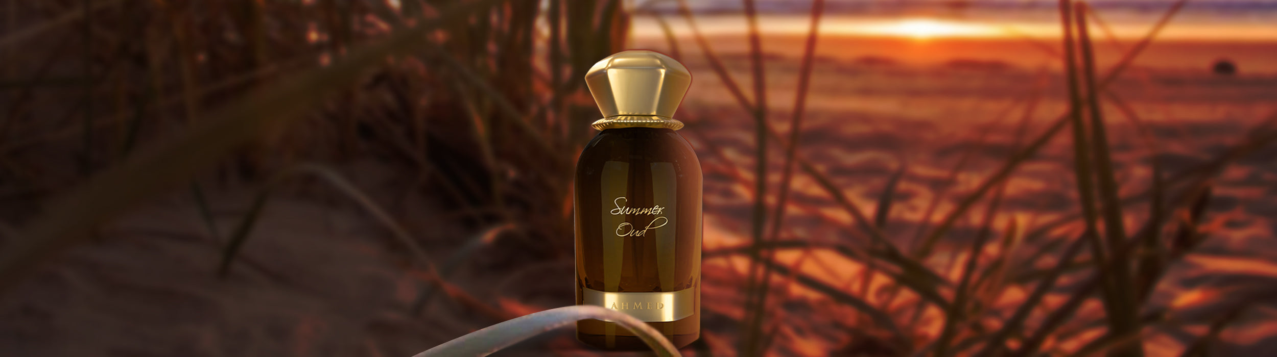 Summer Oud Perfume bottle with a sunset or sunrise in the background